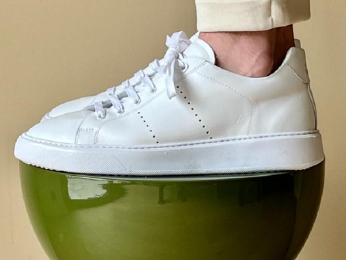 Premium white National Standard sneaker on a green stool, ethical Portuguese craftsmanship