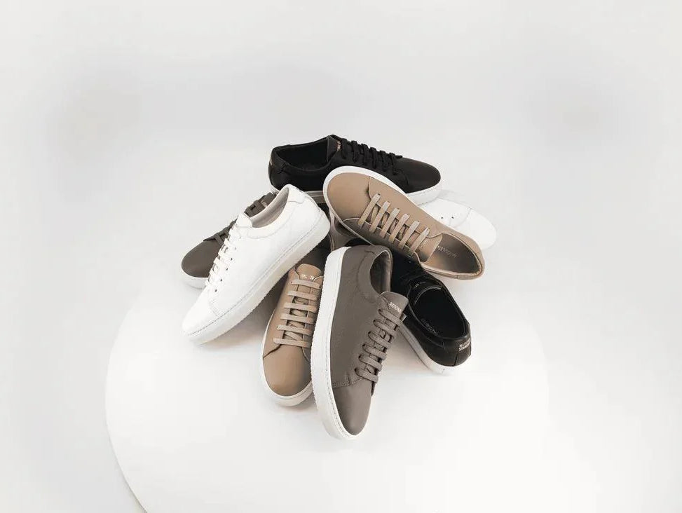 Pile of National Standard premium sneakers in neutral tones on a white background