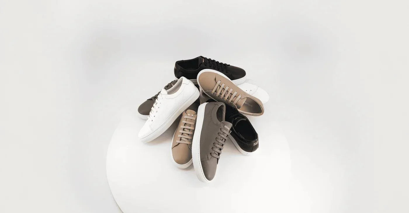 Pile of National Standard premium sneakers in neutral tones on a white background